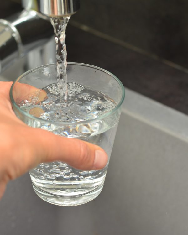 A woman's hand pours water into a glass